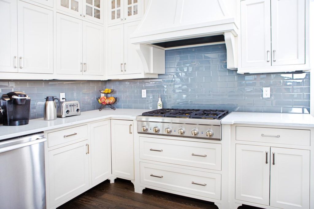 minimalist kitchen design featuring white shaker cabinets with blue tile backsplash